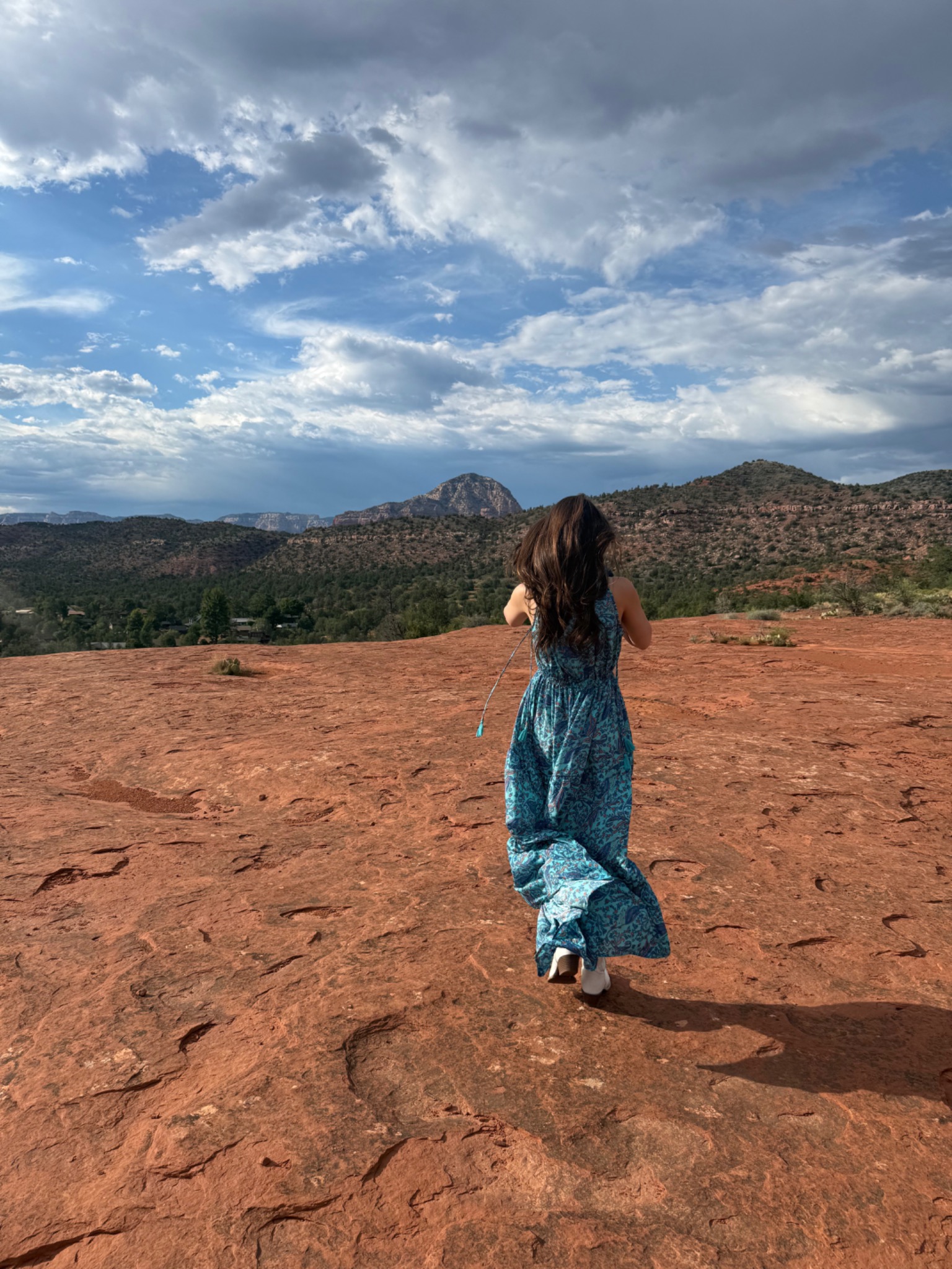 Jacquelyn moving through the Sedona red rocks in a blue dress